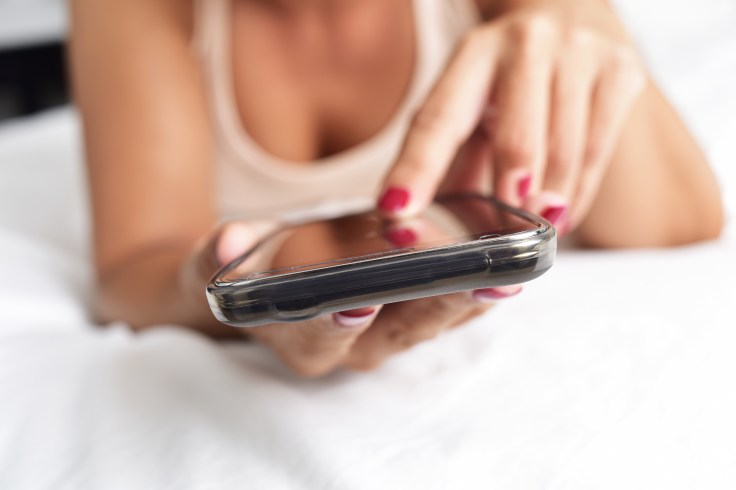 young woman using a smartphone in bed